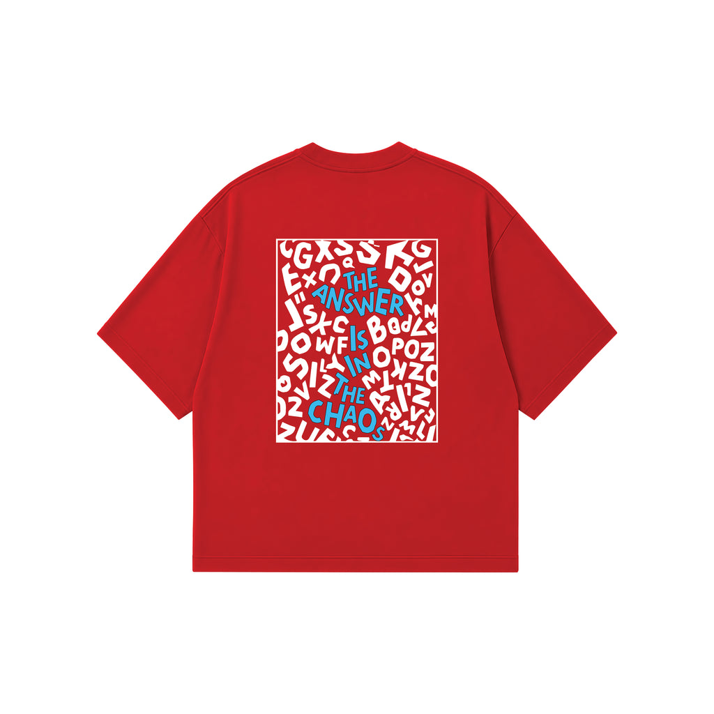 A red short-sleeve t-shirt with a square graphic print on the back, featuring a white background filled with white abstract shapes and blue text that reads 'THE ANSWER IS IN THE CHAOS'.