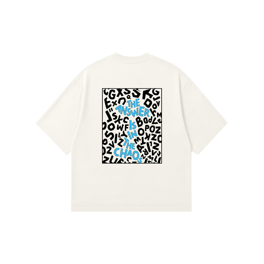 An off-white short-sleeve t-shirt with a square graphic print on the back, featuring a white background filled with black abstract shapes and blue text that reads 'THE ANSWER IS IN THE CHAOS'.