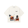 An off-white short-sleeve t-shirt with a colorful graphic print on the front featuring the text 'a hot mess.' in a comic-style font, a cartoon skeleton, and small star details.