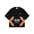 A black short-sleeve t-shirt with a graphic design featuring two orange hands reaching toward white spiral shaped face, with the text saying "the edibles has started asking questions" and brand name 'tangnt' printed on the chest.