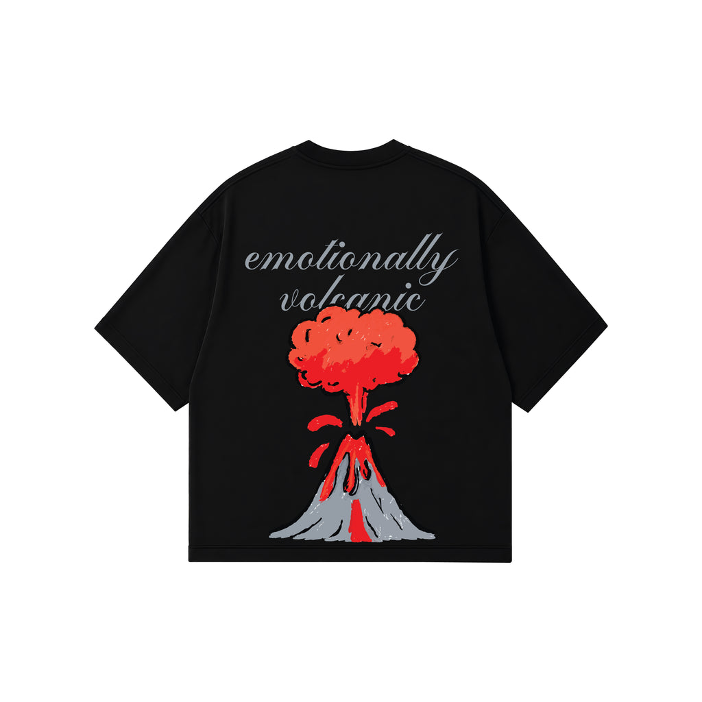 A black short-sleeve t-shirt with a graphic of an erupting volcano and the text 'emotionally volcanic' in grey script, displayed on a solid white background.