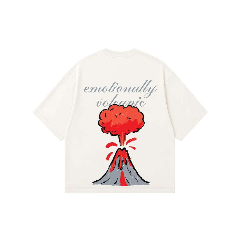 An off-white short-sleeve t-shirt with a graphic of an erupting volcano and the text 'emotionally volcanic' in grey script, displayed on a solid white background.